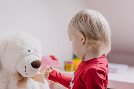 toddler standing in front of white bear plush toy thumbnail