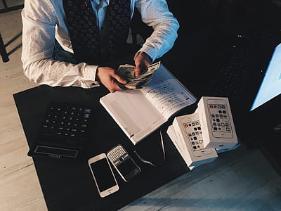 Person Counting Money With Smartphones in Front on Desk thumbnail