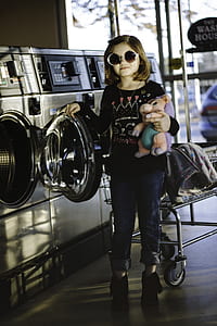 girl standing beside washing machine with her right hand on washing machine door thumbnail