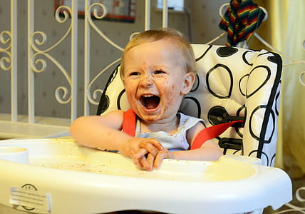 baby wearing white sleeveless top sitting on high chair thumbnail