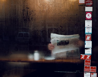 person reading newspaper inside dark room thumbnail