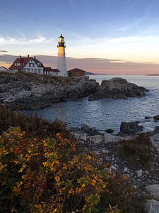 white lighthouse near sea under blue sky thumbnail