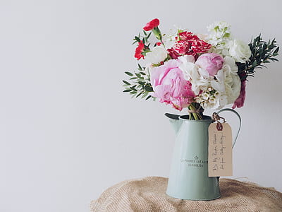 white and pink rose flowers in white steel pitcher on brown cloth thumbnail