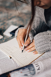 Woman in a grey sweater taking notes in an organizer thumbnail