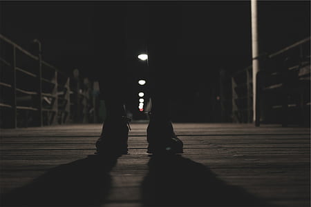 silhouette photo of person standing on bridge in front of railed post lights thumbnail