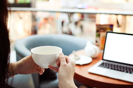 Person Holding White Ceramic Teacup in Front of a Macbook Pro thumbnail