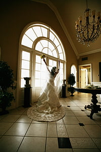 woman wearing white wedding dress raising hands near glass window thumbnail