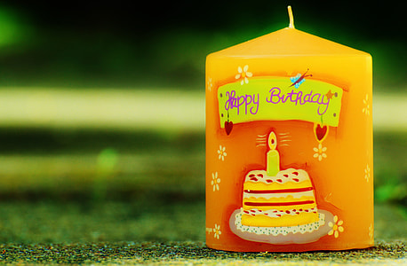 selective photography of yellow Happy Birthday pillar candle thumbnail