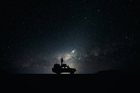 silhouette of person standing on vehicle at nighttime thumbnail