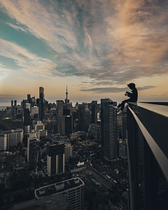 person sitting on the top of building photography during daytime thumbnail