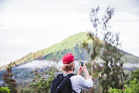 A hiker clicking picture from his mobile phone in the forest thumbnail