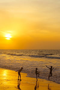 three people walking on seashore under golden hour thumbnail