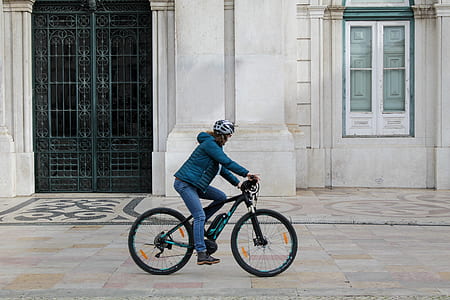 person biking in front of white building thumbnail