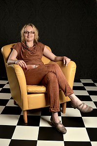 smiling woman sitting on yellow leather armchair thumbnail
