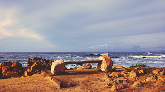 wooden bench near ocean under blue sky during daytime thumbnail
