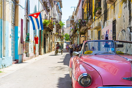 classic pink convertible car parked near concrete buildings at Cuba during daytime thumbnail