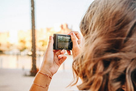 selective focus photography of person using camera during daytime thumbnail
