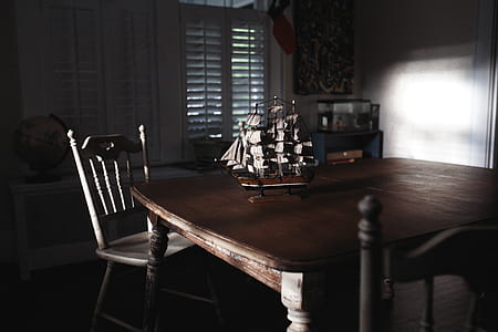 sunlight reflecting on galleon scale model on top of table near chair thumbnail