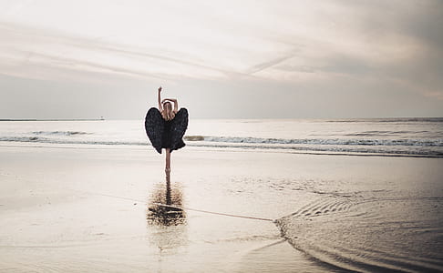 woman wearing black angel wings standing on seashore thumbnail