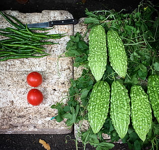 five green bitter melons beside of two red tomatoes thumbnail