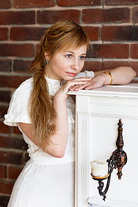 woman resting chin on her right hand standing beside white cabinet thumbnail