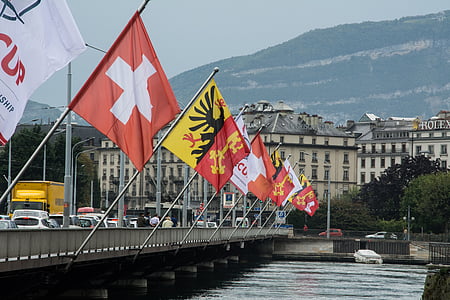 assorted-color flag post on gray bridge near water during daytime thumbnail