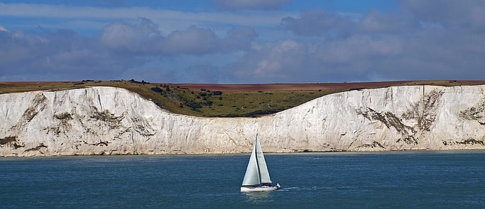 sailboat near cliff during daytime thumbnail