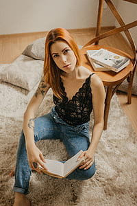 woman sitting on white area rug near brown wooden chair inside room thumbnail
