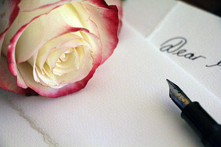 white and red flower beside fountain pen thumbnail