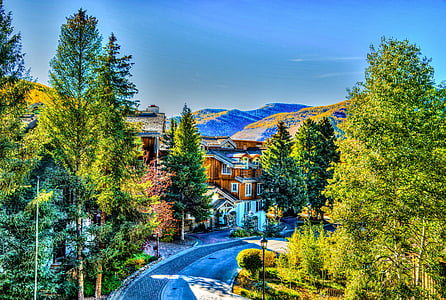 brown concrete 3-storey house between trees background of mountain view beside road thumbnail