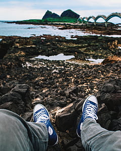 person sitting on stone in front of body of water thumbnail