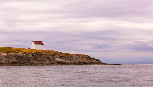 white and red house on hill near body of water thumbnail