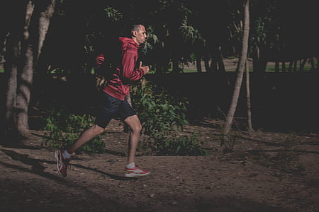 man wearing red hoodie running near plants and tree thumbnail