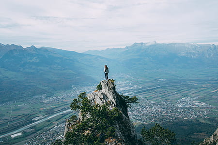 person standing on top of cliff facing landscape thumbnail