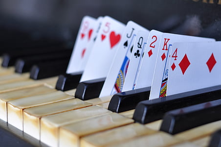 close up photography of playing cards put in between piano keys thumbnail