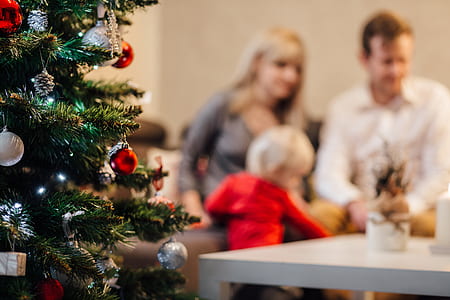 man in white sweater beside woman gray long-sleeved shirt near green Christmas tree thumbnail