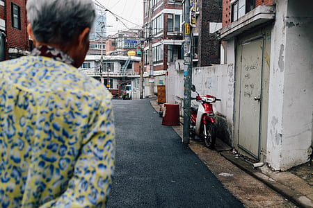 person looking on red and white motor scooter parking near white wall thumbnail