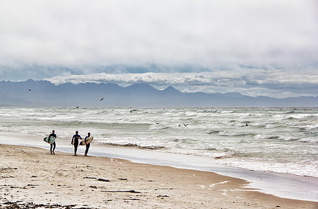 three persons holding surfboards walking near seashore thumbnail