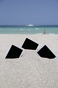three black frames on white sand by the beach thumbnail