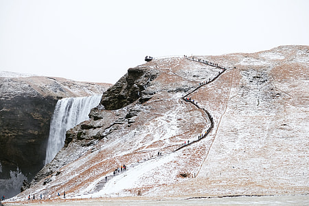 people climbing on a rocky mountains with waterfalls during daytime photography thumbnail