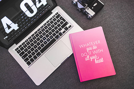Pink notebook with a silver laptop and a camera thumbnail