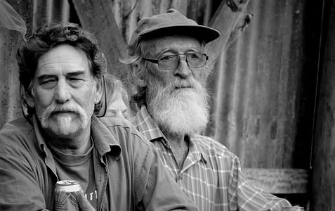 grayscale photography of two men sitting beside each other thumbnail