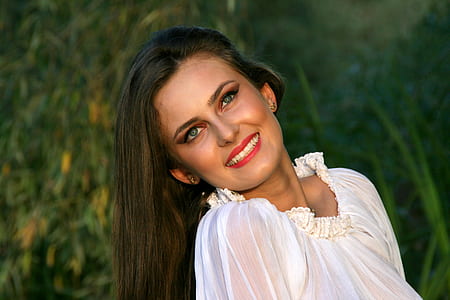 smiling woman posing near green grass outdoors thumbnail