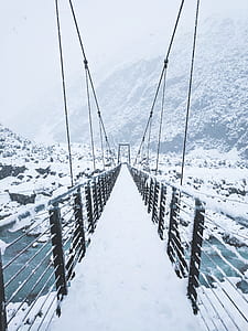 bridge above body of water covered with snow near mountain thumbnail