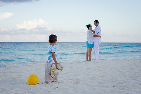 boy wearing white t-shirt staring on man and woman standing on shoreline thumbnail