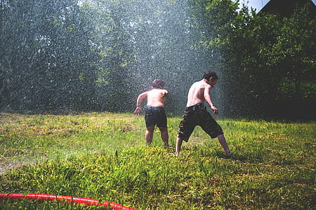 two boys playing on water sprinkler thumbnail