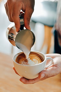 person pouring cream on cappuccino coffee thumbnail