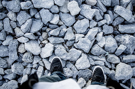 person wearing black-and-white sneakers and gray pants standing over gray gravel ground thumbnail
