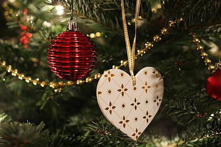 red bauble and white heart ornament hanged on green Christmas tree thumbnail