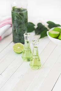 two filled clear glass bottles beside leaves and fruits thumbnail